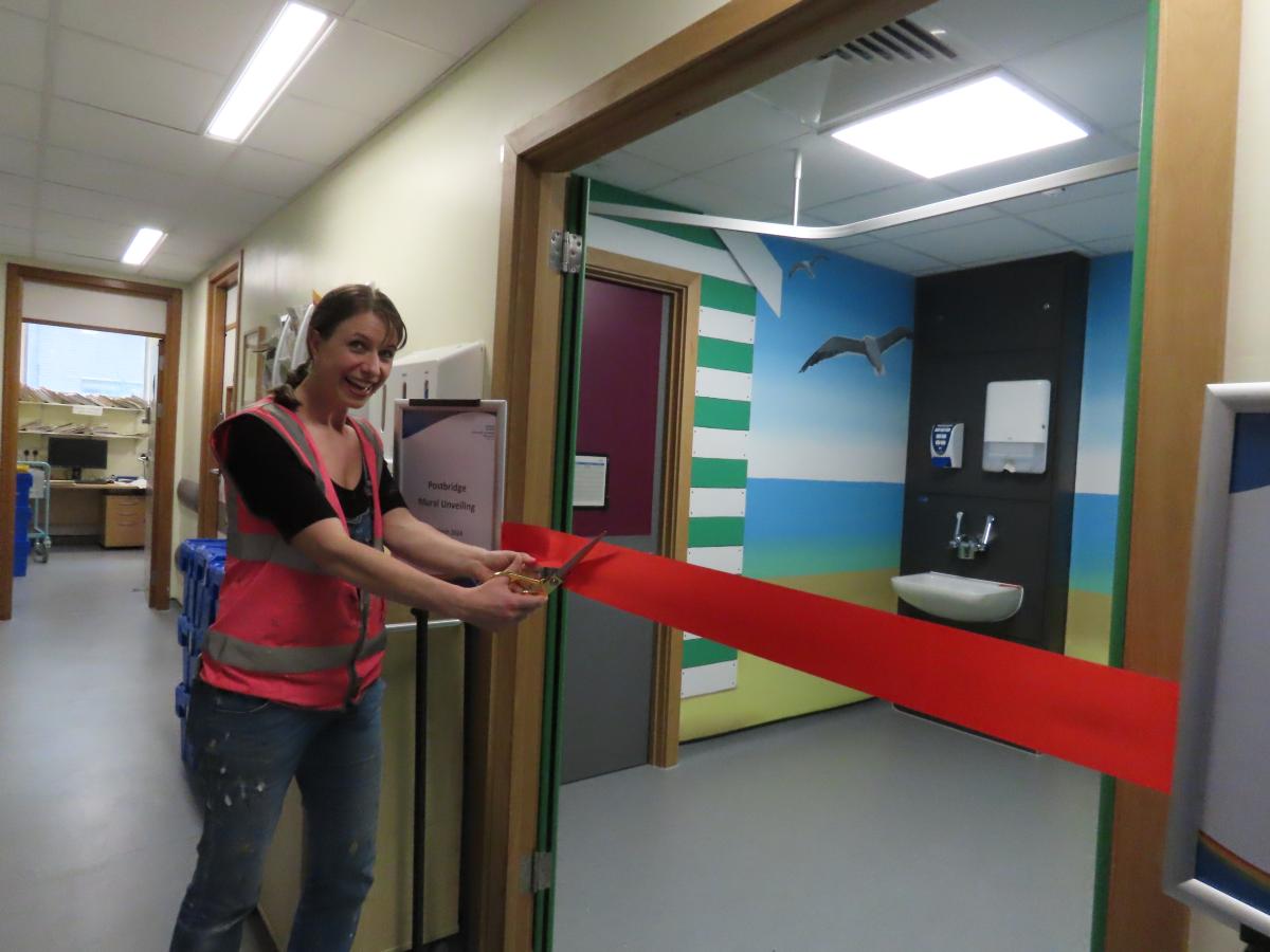 Mrs Murals cutting a red ribbon at the entrance to Postbridge Ward