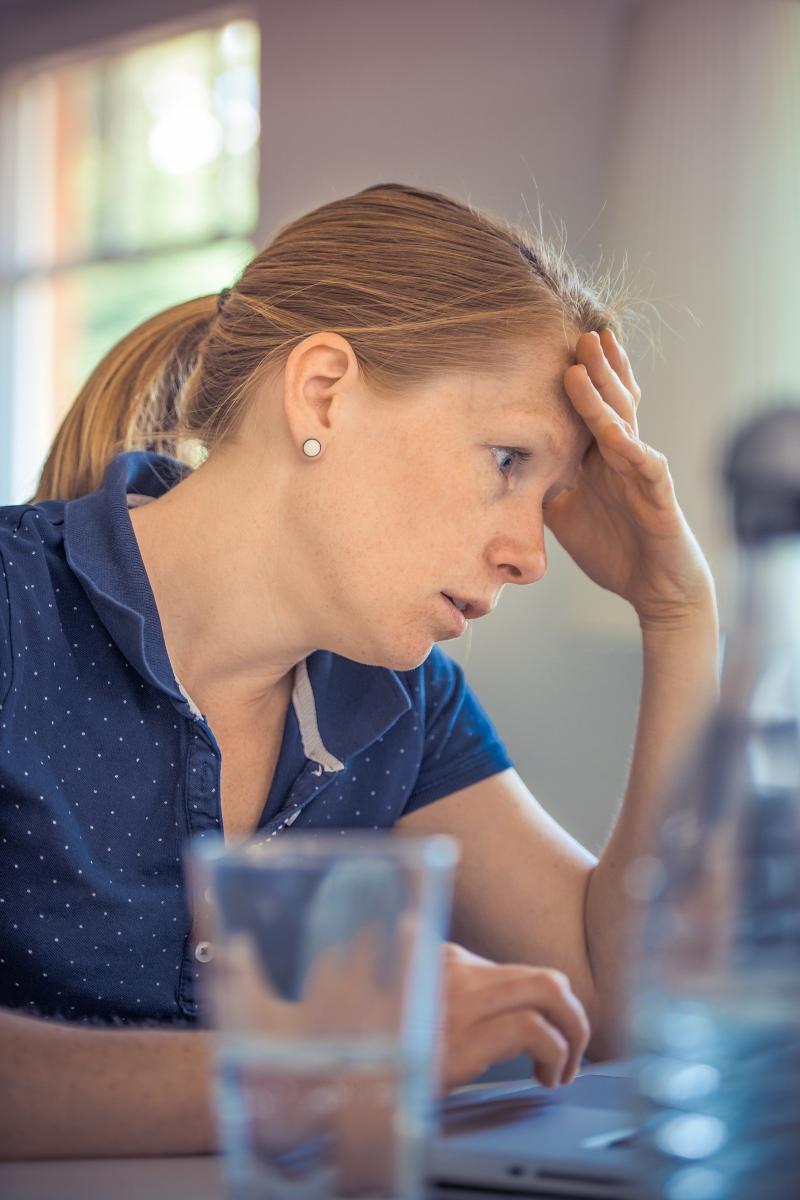 A woman is sitting at her desk looking anxious and worried