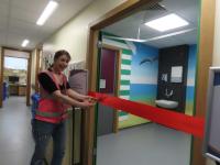 Mrs Murals cutting a red ribbon at the entrance to Postbridge Ward