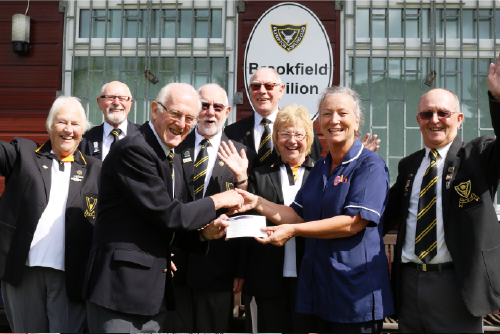 Photo of member of staff collecting a cheque from Brookfield Bowling Club