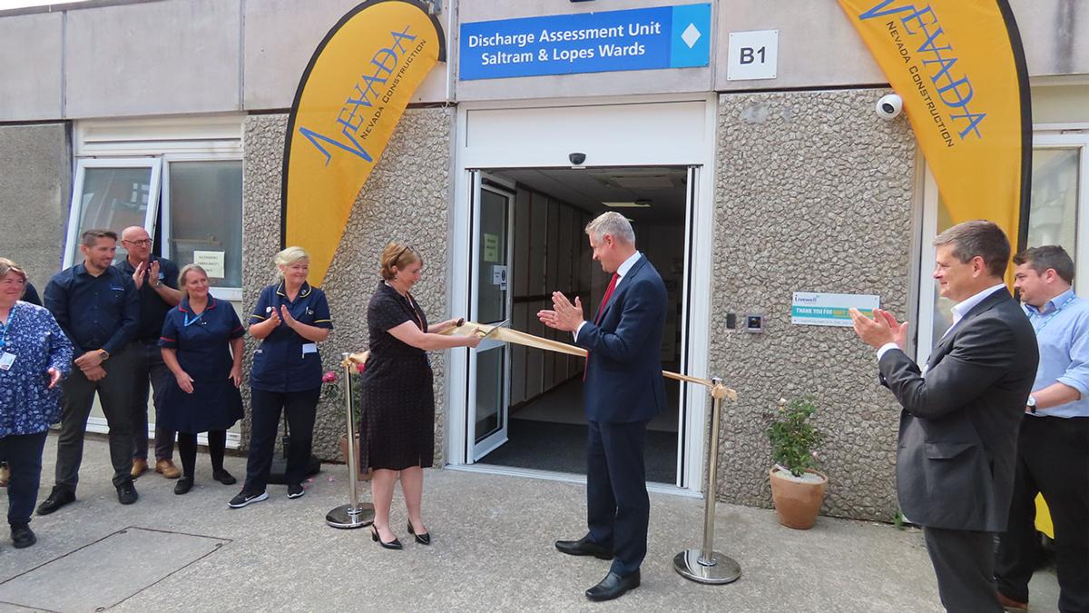 Opening of Discharge Assessment Unit. A yellow ribbon is across the open doors and about to be cut.