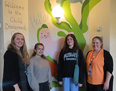 Emma Fawkes, Lead Nurse for Children’s Bladder and Bowel Care and Dr George Davis, Lead for the Children’s Psychological Health and Wellbeing team, joined by University of Plymouth illustration students Mia Ingleby and Martha Pengelley, stood side by side in front of a mural of a seal in the Child Development Centre