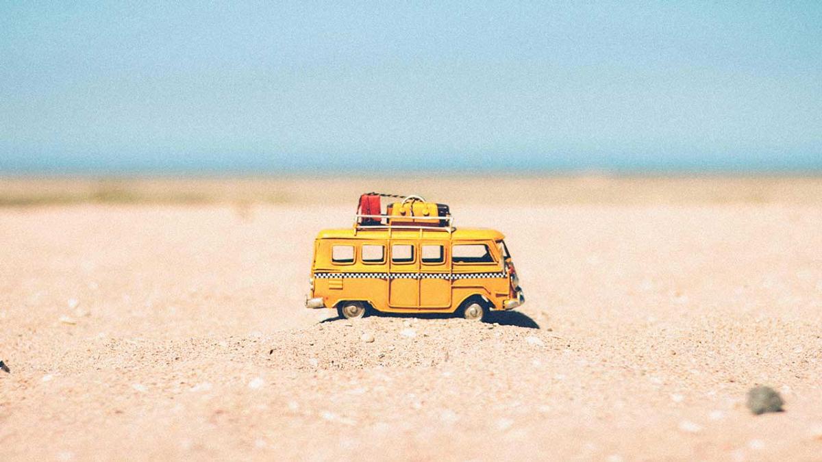 Yellow die-cast miniature van on brown sand
