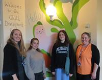 Emma Fawkes, Lead Nurse for Children’s Bladder and Bowel Care and Dr George Davis, Lead for the Children’s Psychological Health and Wellbeing team, joined by University of Plymouth illustration students Mia Ingleby and Martha Pengelley, stood side by side in front of a mural of a seal in the Child Development Centre